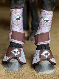 the legs and feet of a horse wearing boots with flowers on them, in front of a brown background