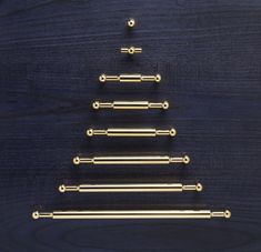 a christmas tree made out of brass rods on a wooden surface with space for text