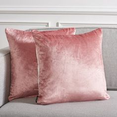 two pink velvet pillows on a grey couch