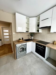 a kitchen with white cupboards and an oven in the corner next to a washer and dryer