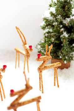 four reindeer made out of pretzels in the snow next to a small christmas tree