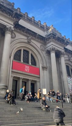 people are sitting on the steps in front of a building