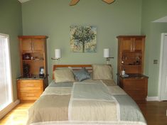 a bedroom with a bed, dressers and other items in the room that is painted light green