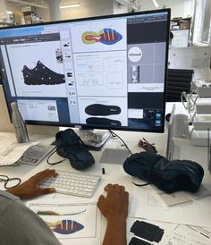 a man sitting at a desk working on a computer screen with his feet propped up in front of the monitor