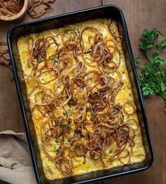 a casserole dish with onions and cheese in a black pan on a wooden table