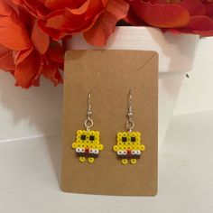 a pair of yellow and black beaded earrings sitting on top of a flower pot