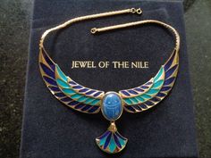 "This is a Gorgeous Vintage FM by Franklin Mint Jewel of the Nile Deep Blue Cabochon Onyx Scarab 22 Karat Gold Electroplate Enameled With Vibrant Blue and Aqua Pharaoh Necklace Ancient Egyptian Style Jewelry The Jewel of the Nile Necklace was electroplated with 22 karat gold and hand enameled with vibrant blue and aqua. At its center is an ageless symbol of good luck that dates from the time of the pharaohs in Ancient Egypt. This symbol - the scarab - was hand-carved from a color-enhanced deep b Collectible Blue Inlay Necklace, Ceremonial Blue Enamel Jewelry, Traditional Blue Cabochon Necklace, Traditional Blue Cabochon Necklaces, Egyptian Style, Green Aqua, The Nile, Franklin Mint, Ancient Jewelry