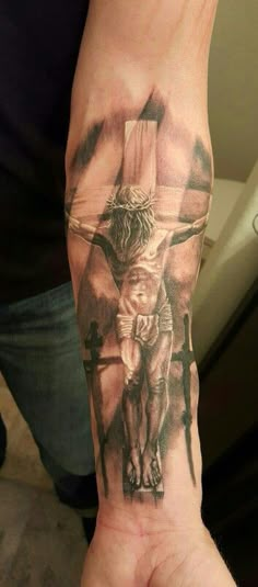 a person with a tattoo on their arm holding up a cross and jesus's crucifix