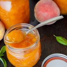 there is a jar of peach jam next to some peaches