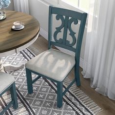 two blue chairs sitting next to each other on top of a rug in front of a window