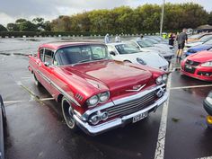 an old red car parked in a parking lot