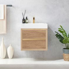 a white sink sitting next to a wooden cabinet and potted plant on top of a counter