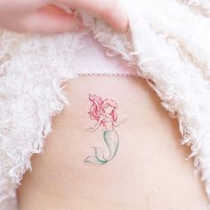 a little mermaid tattoo on the back of a woman's rib - up stomach