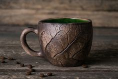 a coffee cup that is sitting on a table with some coffee beans scattered around it