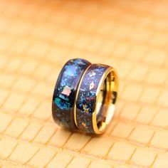 two rings with blue and green glitters on them sitting on top of a table