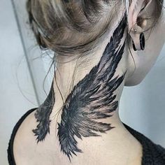 the back of a woman's neck is covered in black ink with an angel wing tattoo on it