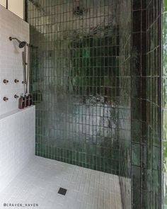 a bathroom with green tile and white tiles on the shower wall is pictured in this image