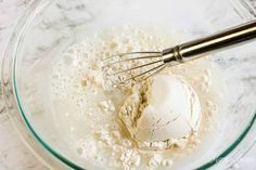 a whisk in a glass bowl filled with flour