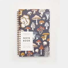 a notebook with mushrooms on it and the words note book written in white ink is shown