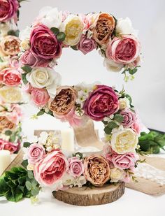 the letter g is decorated with flowers and greenery on top of a white table