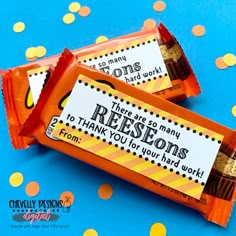 two candy bar wrappers sitting on top of a blue and yellow tablecloth with confetti scattered around them