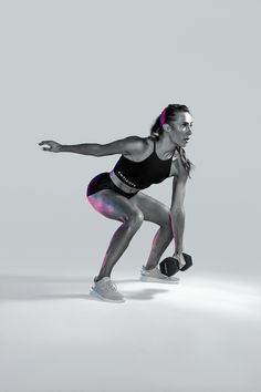 a woman in black shirt and pink leggings squatting on a white surface