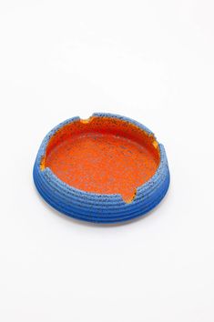 an orange and blue dish sitting on top of a white table