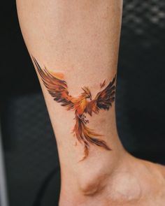 a woman with a tattoo on her ankle has a red and yellow bird design on it's leg