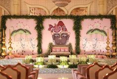 an elaborately decorated room with pink walls and green garlands on the wall, surrounded by gold chairs