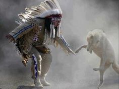 a man in native clothing playing with a dog