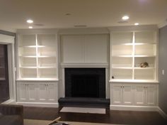 an empty living room with built - in bookcases and a large fire place