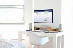 a desktop computer sitting on top of a white desk next to a bed in a bedroom