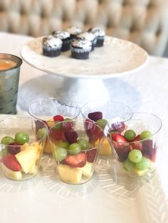 small cups filled with fruit sitting on top of a table next to a tray of cupcakes