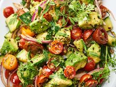 a salad with tomatoes, cucumbers, onions and avocado on it