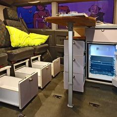 the interior of an rv with storage drawers and couches, including a table that has been converted into a mini - fridge