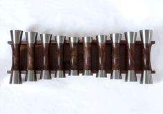 a wooden and metal wall hanging on the side of a white wall with multiple pieces of wood in it