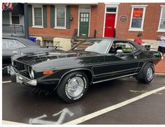 a black car parked in front of a brick building