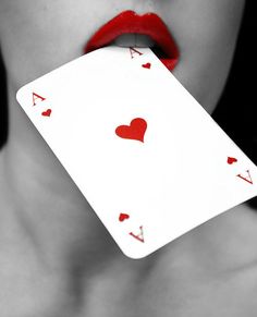 a woman with red lipstick holding up a playing card