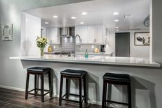 a kitchen with three stools next to a counter top and an island in the middle