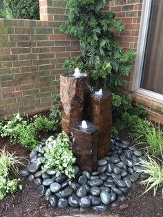 some rocks and trees in front of a brick building with plants growing out of it