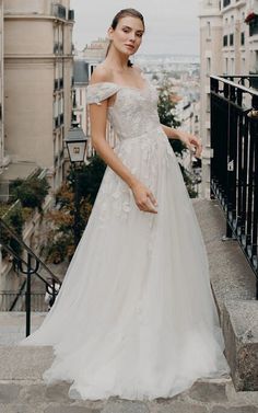 a woman in a white wedding dress standing on some stairs with her hand on her hip