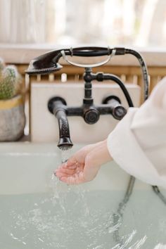 a person washing their hands in a sink with water running from the faucet