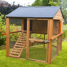 a small chicken coop with stairs to the top and side door open on green grass