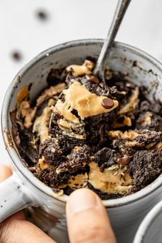 a person holding a spoon in a cup filled with ice cream and chocolate cookie dough