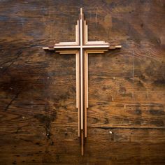 a wooden cross sitting on top of a wooden table next to a wall with wood planks