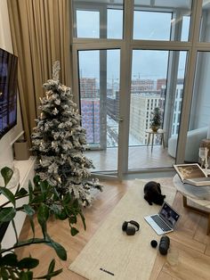 a living room filled with furniture and a christmas tree in front of a large window