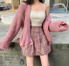 a woman wearing a pink cardigan sweater and plaid miniskirt is posing for the camera