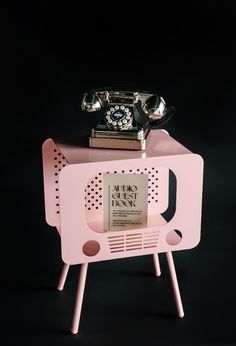 an old fashioned pink radio sitting on top of a table with a phone on it