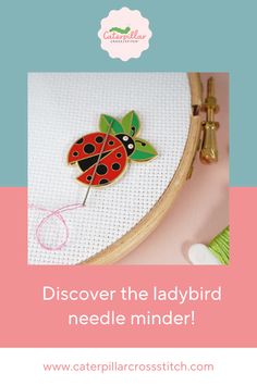 a ladybug pin sitting on top of a piece of fabric next to a needle