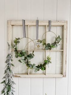 an old window is decorated with wreaths and greenery to hang on the wall